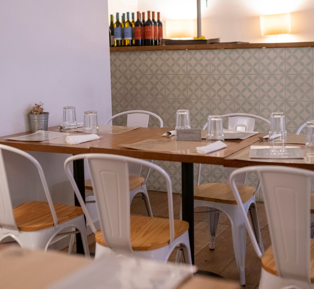 Sala de refeições da Presto Pizza no Porto com mesas de madeira, cadeiras brancas e um resguardo com azulejo verde